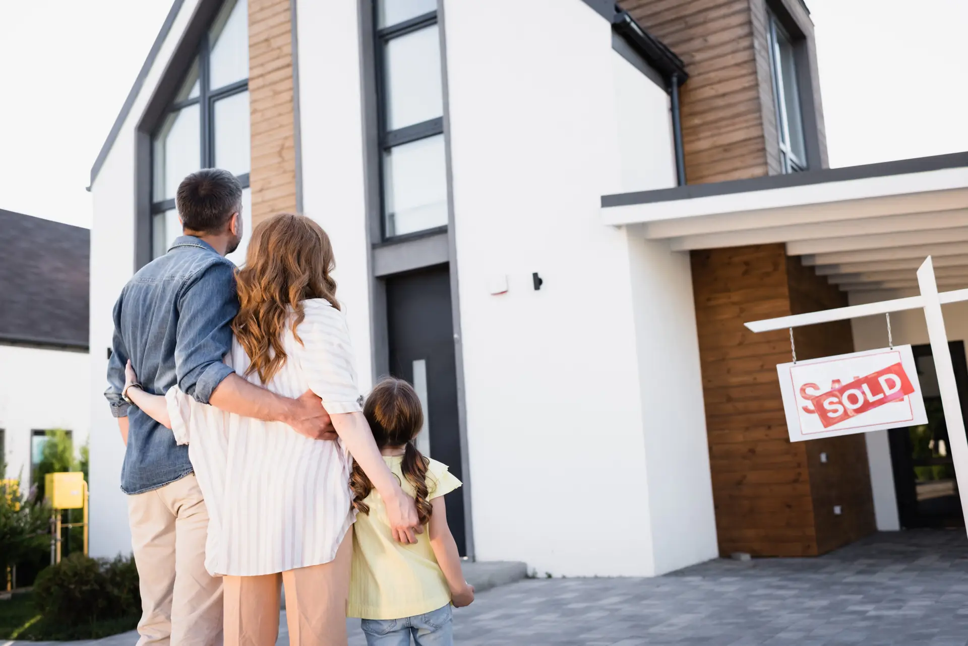 Happy family celebrating home purchase with sold sign after successful home inspection