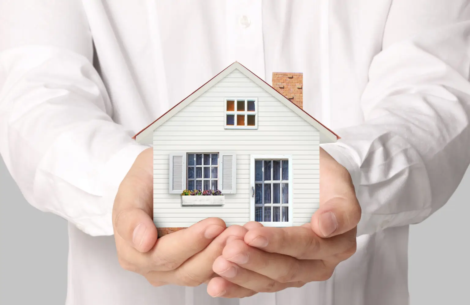 holding house representing home ownership and the Real Estate business