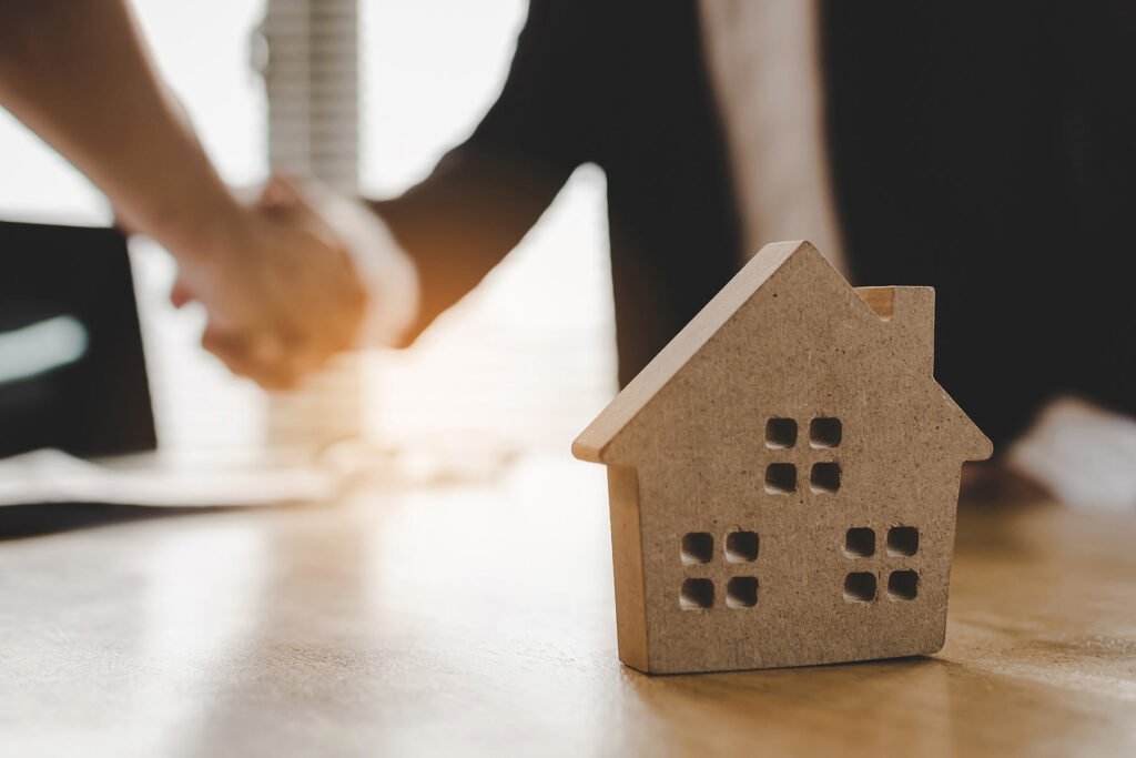 Professional handshake over wooden house model symbolizing successful home purchase agreement, real estate transaction completion, and trusted partnership between homebuyer and home inspection services in Texas