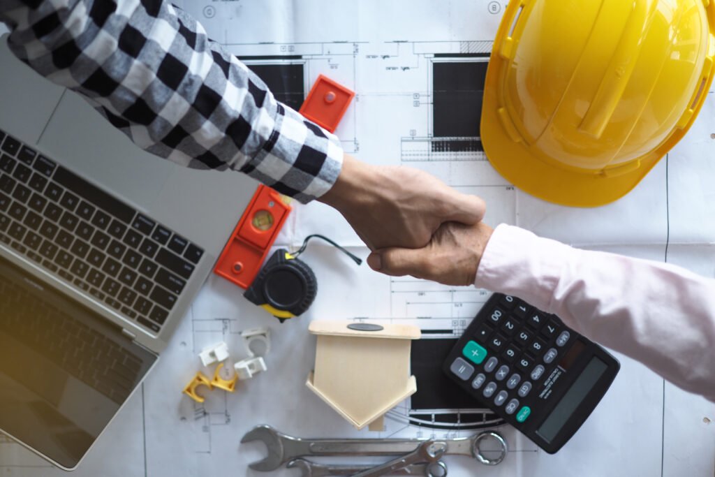 Educational demonstration of construction cost calculation using calculator, blueprints, and laptop for project management learning