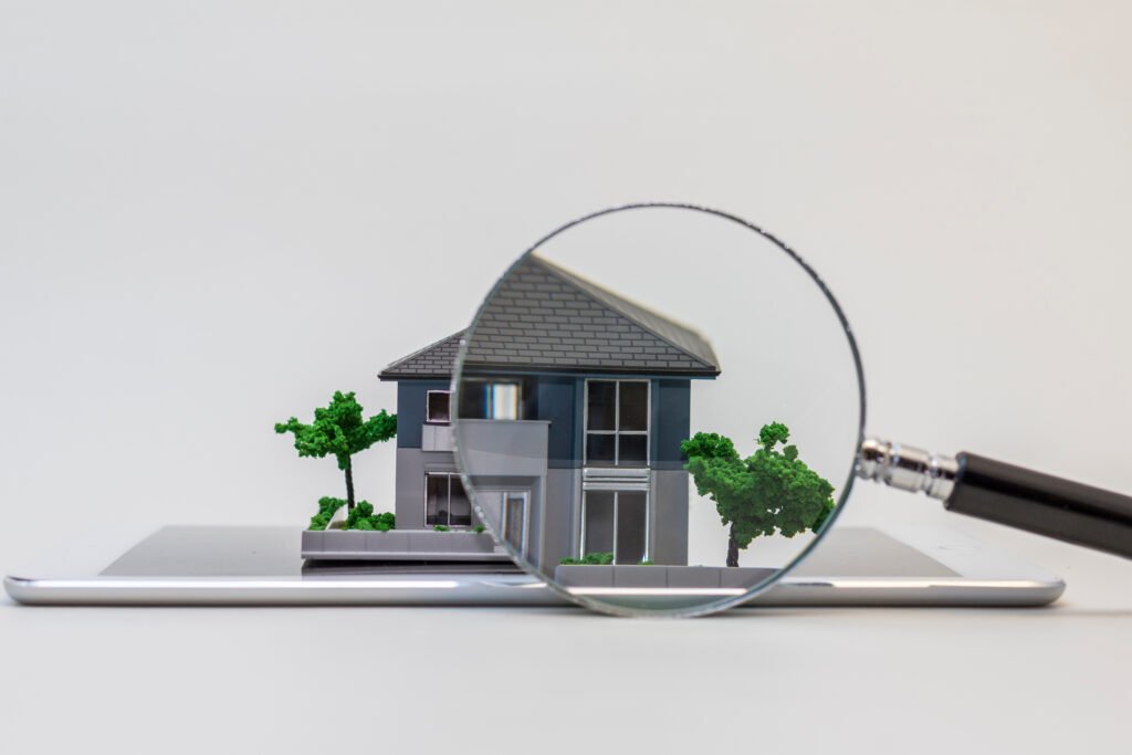 Small white house miniature model with green roof details on white background for architectural design and real estate marketing